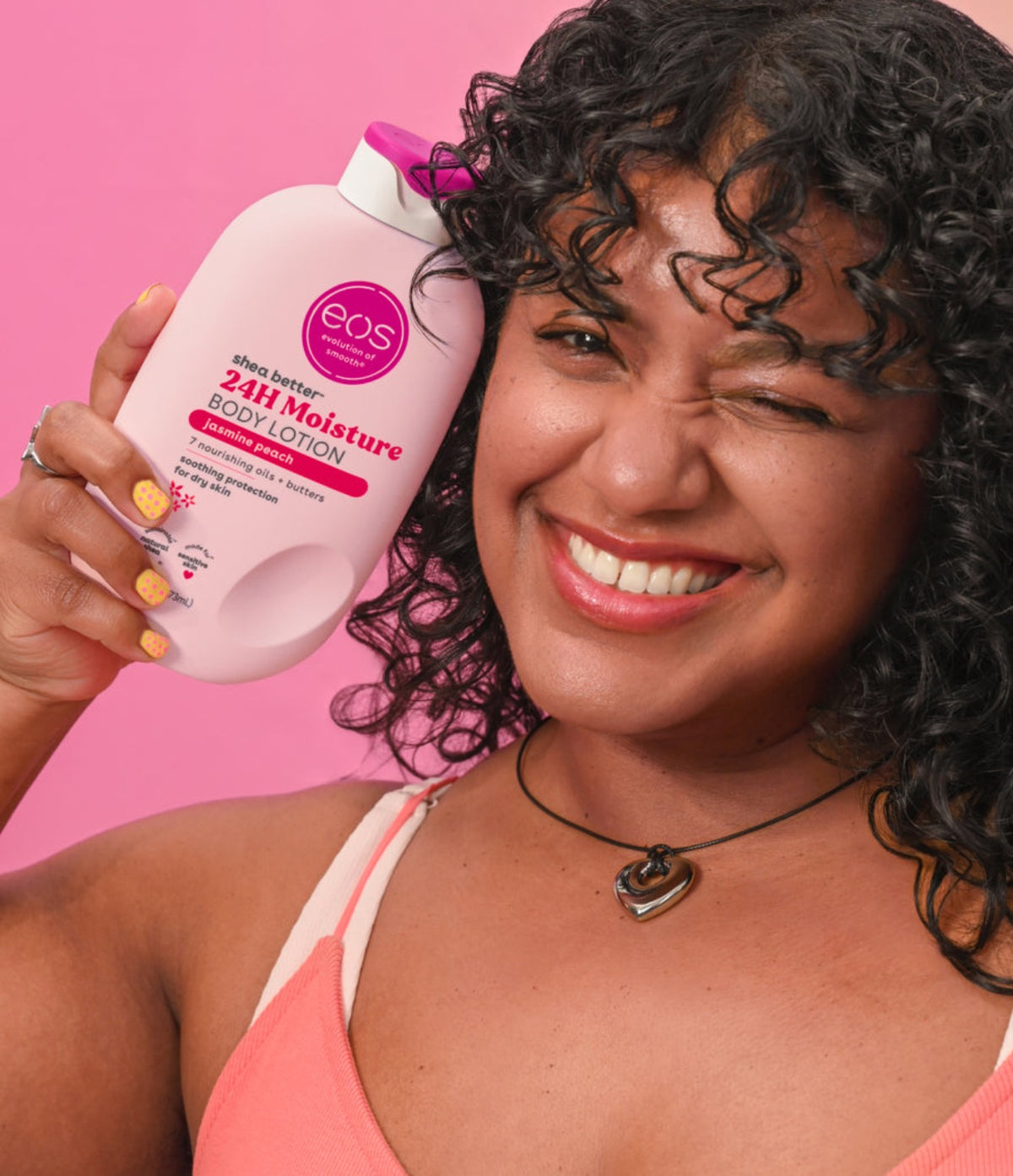 Woman holding EOS Jasmine Peach Body Lotion 473ml against a pink background
