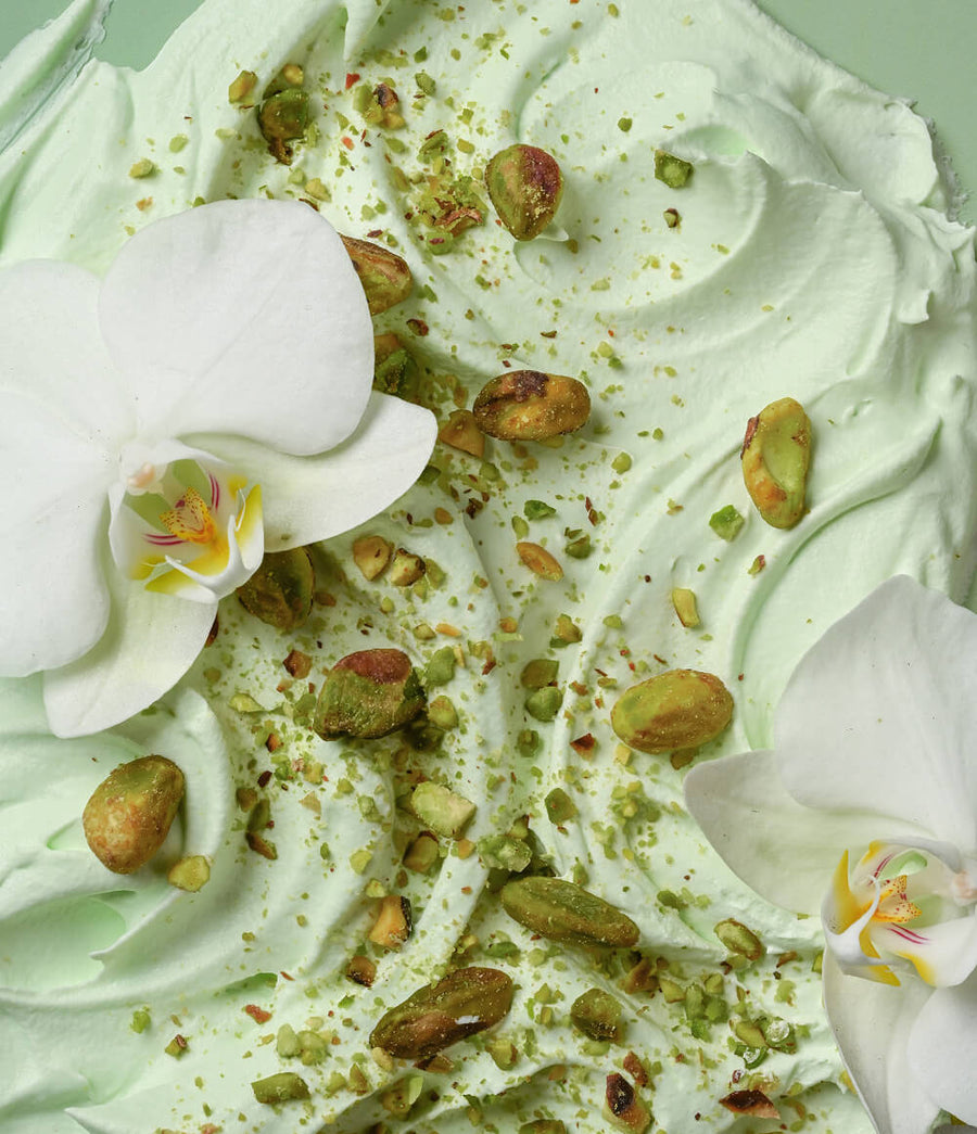 HAMYNAT eos Crème de Pistachio body cream texture with white orchid flowers and crushed pistachio nuts