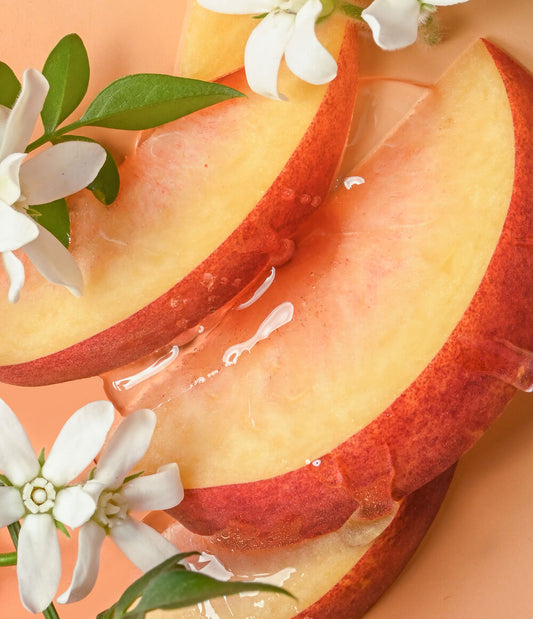 HAMYNAT eos Shea Better Cashmere body wash featuring fresh peach slices and jasmine flowers on a soft peach background