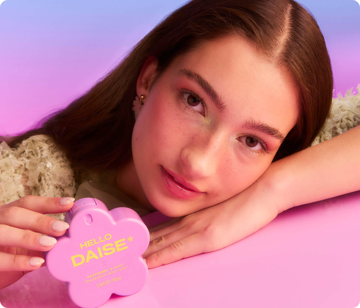 Daise Raspberry & Mint Fragrance Body Mist 100ml held by a model on a pink tabletop