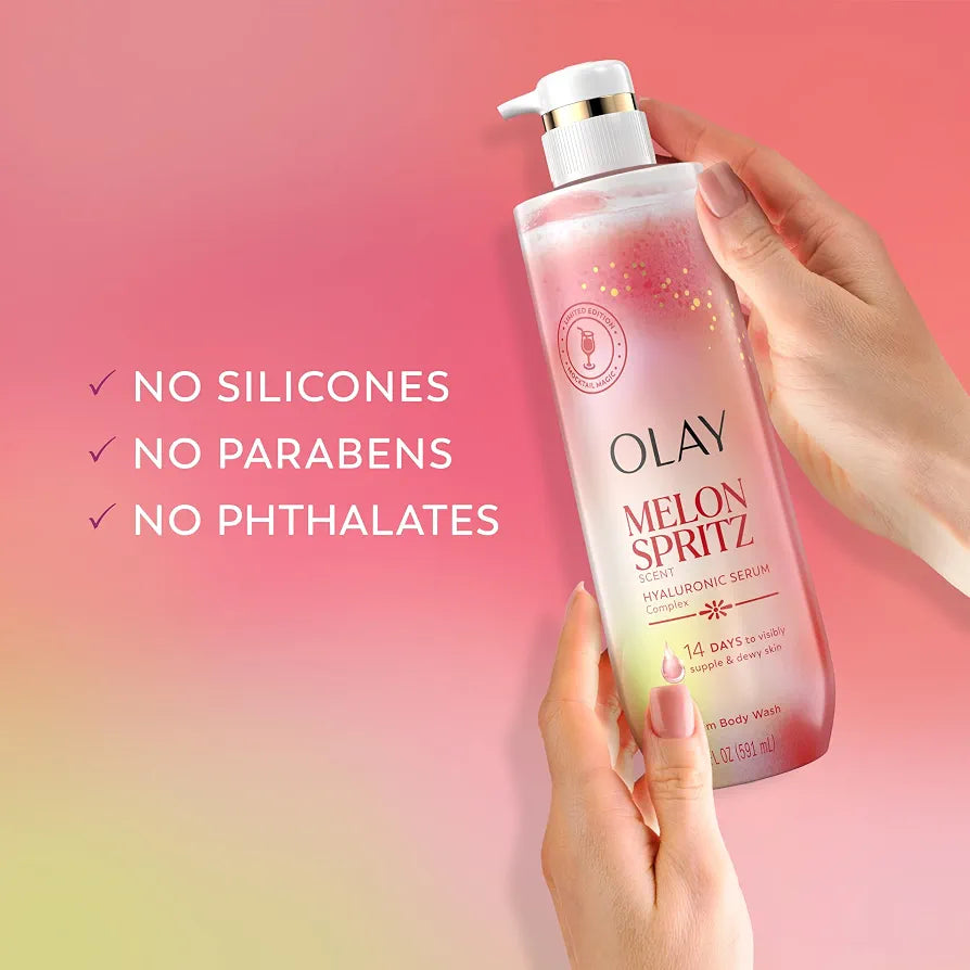 HAMYNAT Olay Melon Spritz Hyaluronic Serum body wash in a pump bottle held by hands against a pink gradient background.