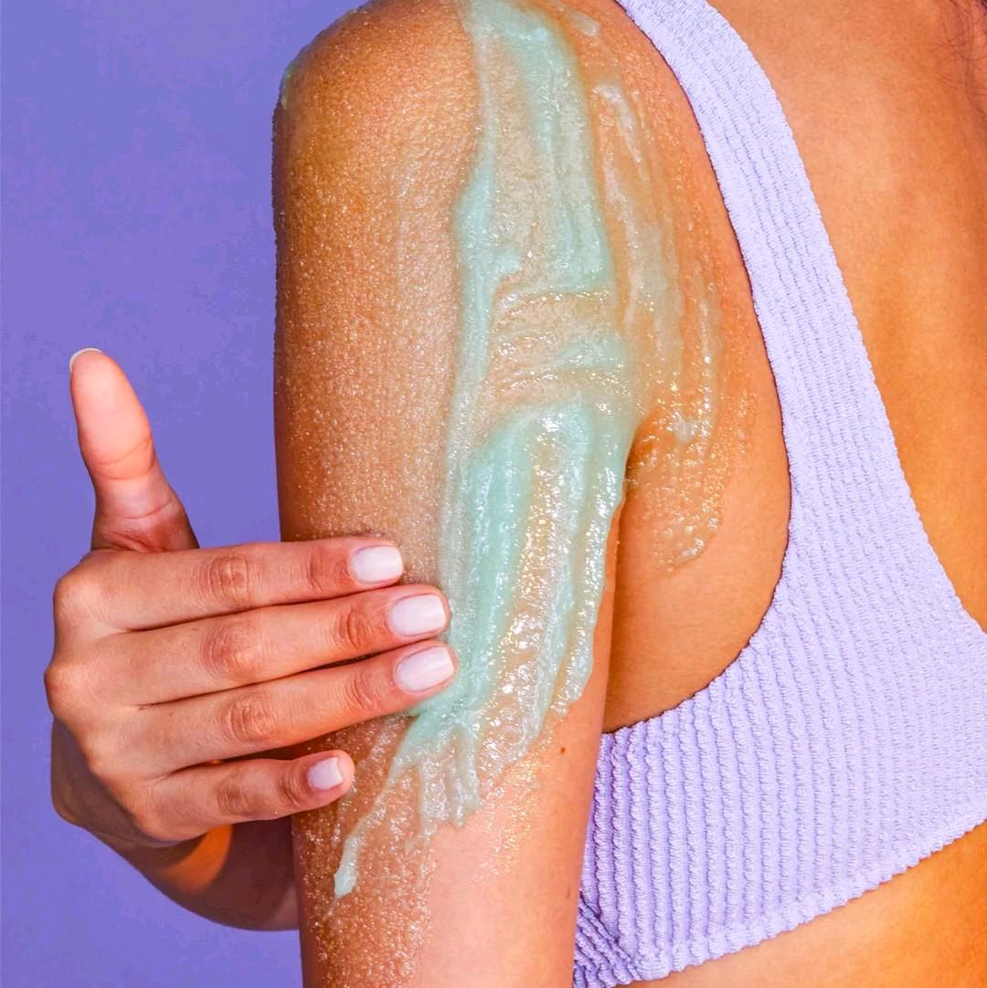 HAMYNAT Tree Hut Aurora Nights shimmering teal sugar body scrub being applied to a model's shoulder for exfoliation