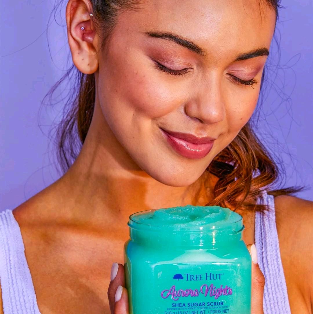 HAMYNAT model holding a jar of shimmering teal Tree Hut Aurora Nights Shea Sugar Body Scrub for skin exfoliation