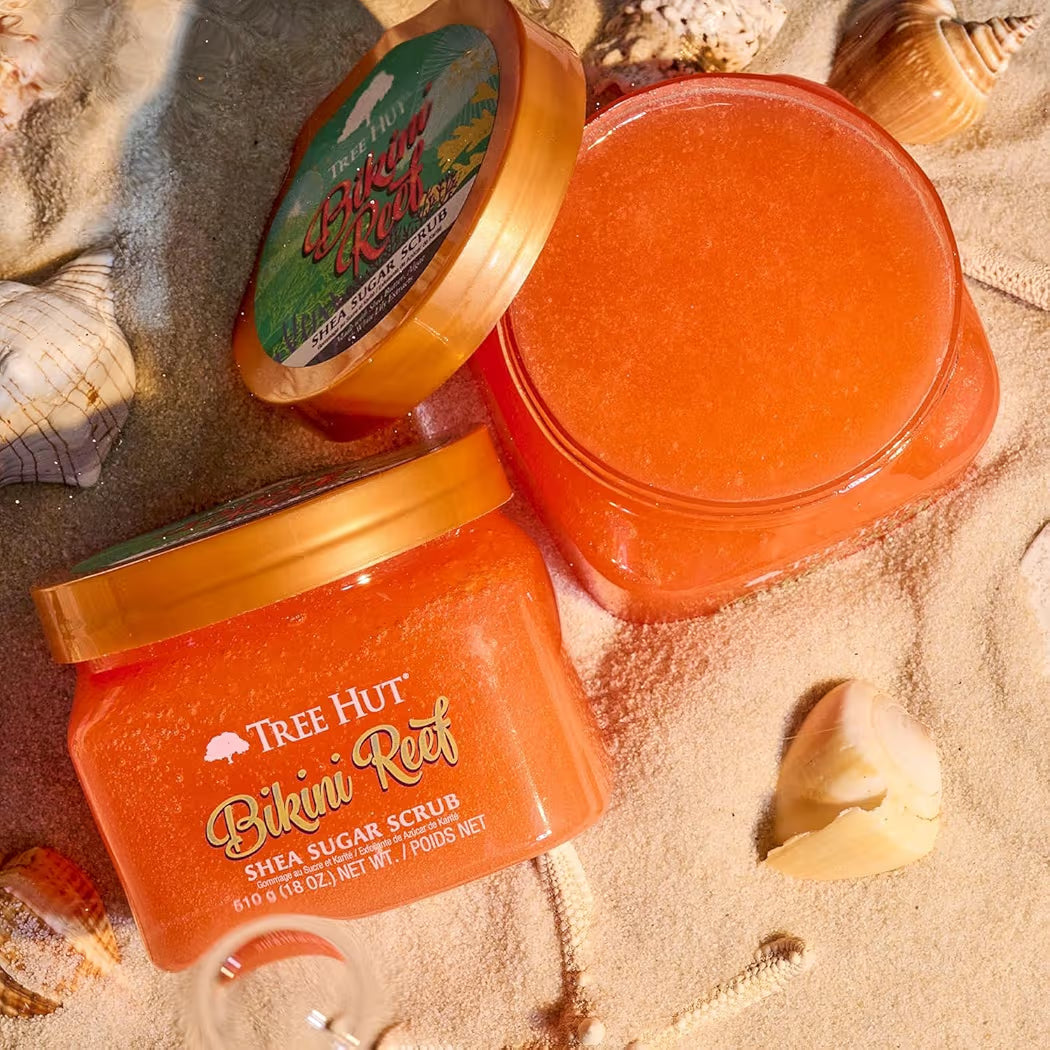 HAMYNAT Tree Hut Bikini Reef Shea Sugar Scrub jars with orange exfoliating texture on a sandy beach with seashells