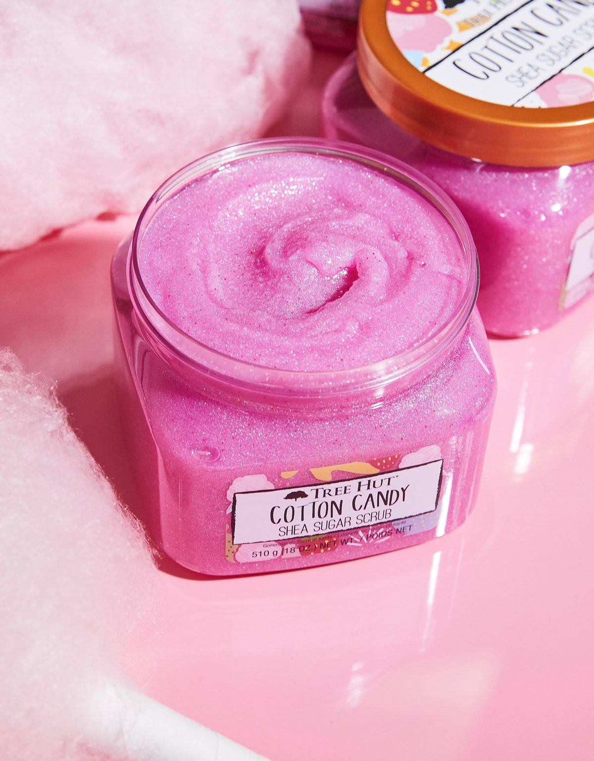 HAMYNAT Tree Hut Cotton Candy Shea Sugar Scrub in a pink, shimmering jar with a gold lid on a pink surface.