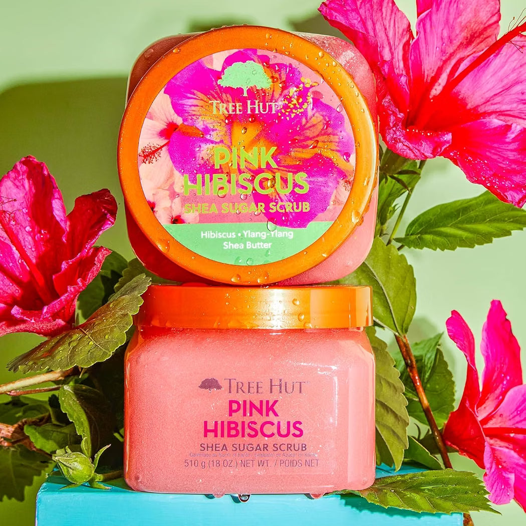 HAMYNAT Tree Hut Pink Hibiscus Shea Sugar Scrub in a pink jar surrounded by vibrant tropical hibiscus flowers.
