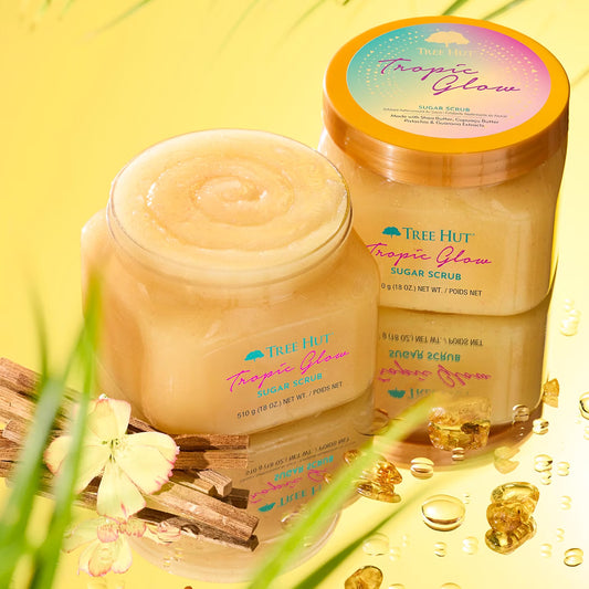HAMYNAT Tree Hut Tropic Glow firming sugar scrub jars with shea and cupuaçu butter on a reflective yellow surface