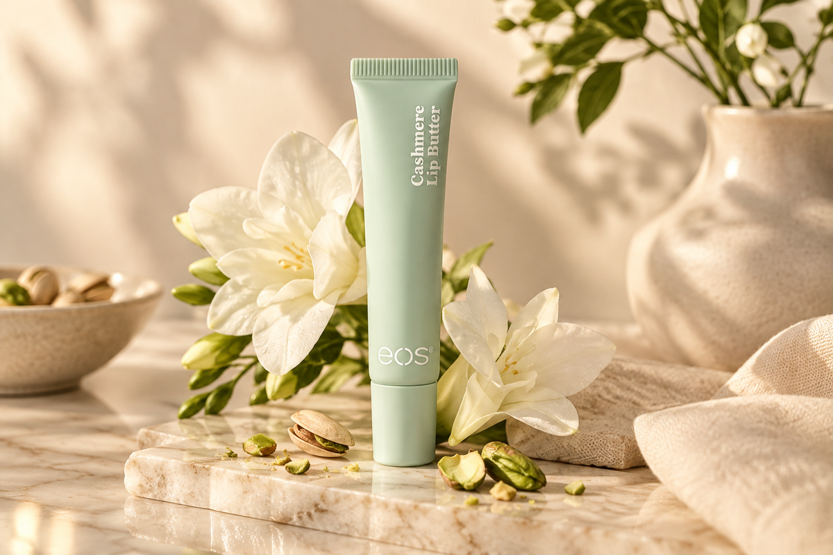 EOS Creme de Pistachio Lip Butter tube standing on a marble surface with white lilies and pistachios