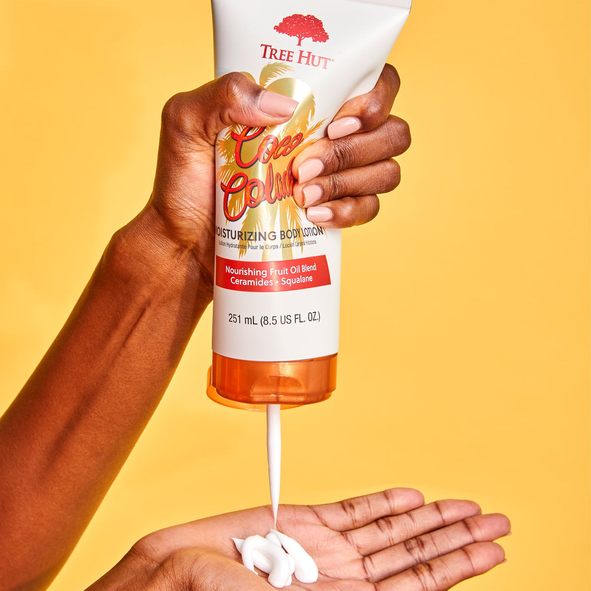 Tree Hut Coco Colada Body Lotion 251ml being squeezed from the tube onto a hand against a yellow background